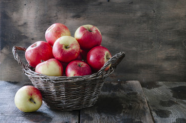Old basket with apples on wooden background