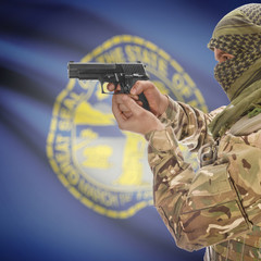 Side view of man in camouflage holding gun against Flag of Nebraska