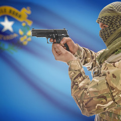 Fototapeta premium Side view of man in camouflage holding gun against Flag of Nevada