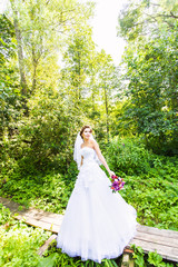 Obraz na płótnie Canvas Beautiful bride outdoors with wedding bouquet