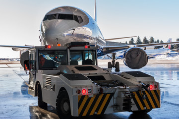 TUG Pushback tractor carries a passenger jet out of hangar