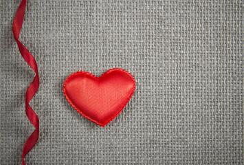 Red textile heart and red ribbon on grey wicker background. Valentines Day card