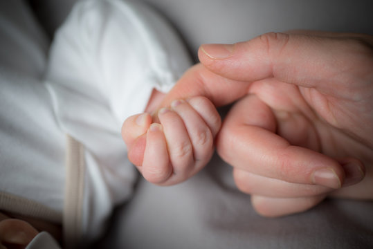 Close up mother's hand holding little hand of her baby
