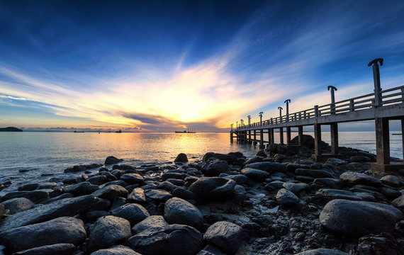 Sea pier sunrise photography with stones and dramatic sky