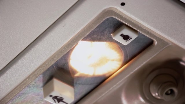 the hand of the stewardess turns on the light over a passenger chair