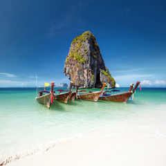 Fototapeta na wymiar Travel photography of wooden boats on shore of tropical sea with scenic rock mountain in water. Vacation journey background of Thailand nature