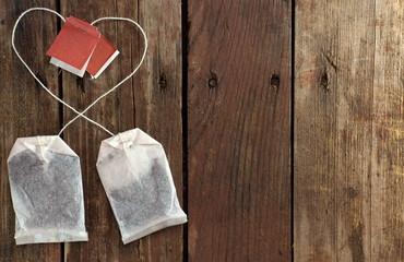 Naklejka na ściany i meble Two tea bags with threads laid out in a heart shape