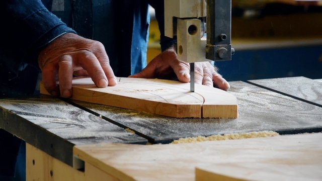 the man on the joiner's machine saws a wooden board