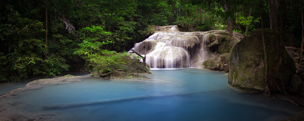 Pond with clear blue water and waterfall in Thailand rainforest. Panoramic nature background