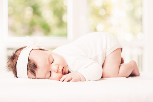 Portrait of sleeping baby in home and window is behaind