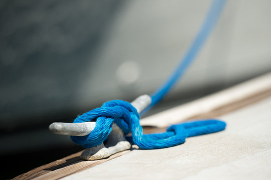 Blue rope tied to metal cleat on boat dock