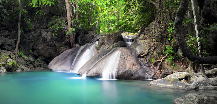Beautiful nature background. Waterfall flows through tropical rainforest and falls into natural pond
