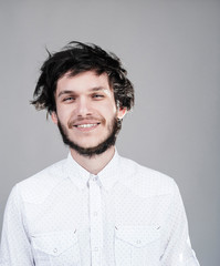 Cheerful young man with a messy hairdo. Light background.