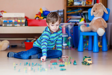 Kid boy playing with toy soldiers indoors at nursery