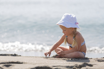 Little girl  sitting on the beach.