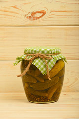 Jar of pickled cucumbers at vintage wood surface