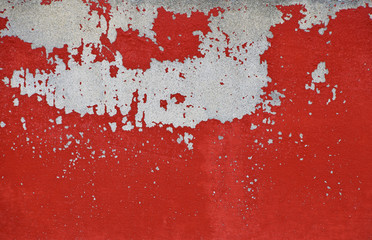 Flakes of old red paint on grey concrete wall