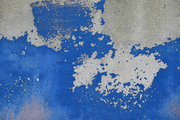 Flakes of old blue paint on grey concrete wall
