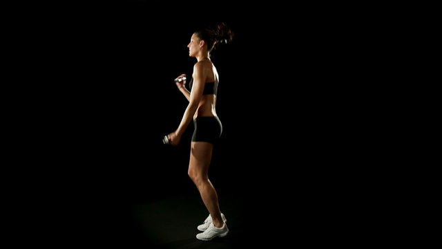 Woman wearing sporstwear is exercising jumping with weights  slow motion  