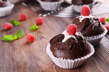 Delicious chocolate cupcakes with berries and fresh mint on wooden table close up