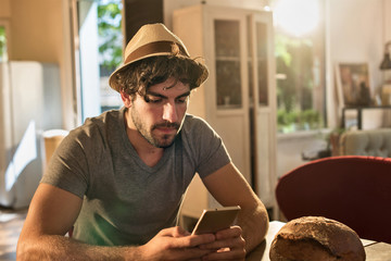 Young man in his 30's with beard and hat, sitting at the table o