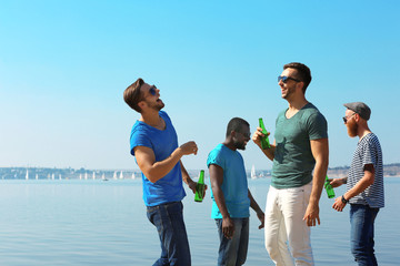 Young men drinking beer on the riverside