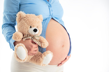 Mom Expecting Baby. Pregnant Woman Holding fluffy bear in her ha