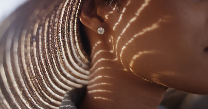 Extreme close up of Black woman with sunhat and diamond earing