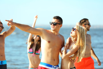 Happy couple and their playful friends relaxing at the beach, outdoors