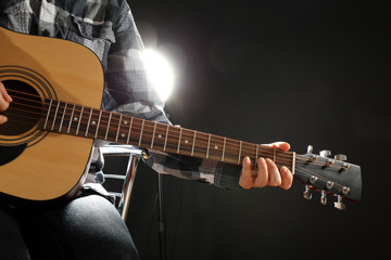 Musician plays guitar on black background, close up