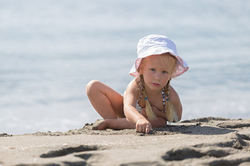 Little girl  sitting on the beach.