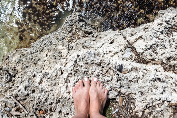 Woman bare feet stand on stone on the beach