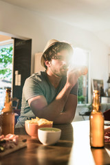Young man in his 30's with beard and hat, sitting at the table 