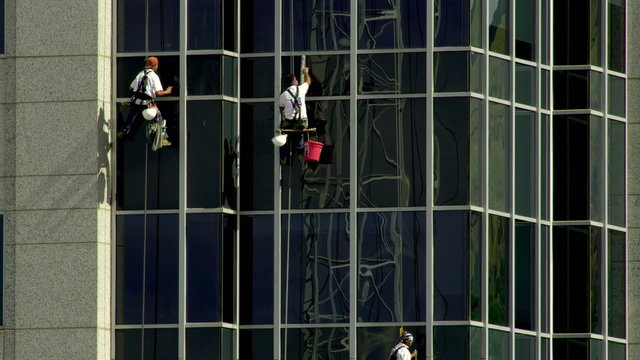 Men rappelling and washing windows at a construction site in SLC Utah.