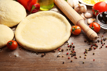 Dough basis and ingredients for pizza, on the table