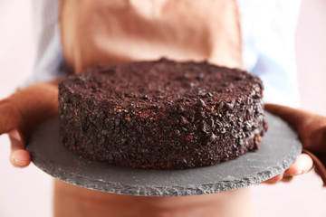 Housewife holding oven-tray with chocolate cake, close up