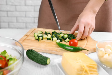 Female hands cutting vegetables for salad, at kitchen