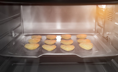 Uncooked heart shaped biscuits on a baking tray in an oven
