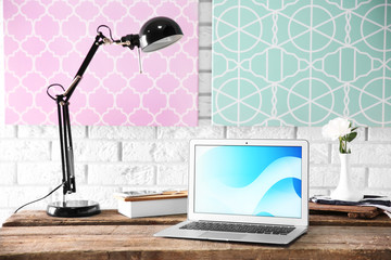 Modern lamp and laptop on table on brick wall background