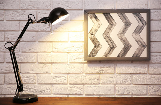 Modern lamp on table on brick wall background
