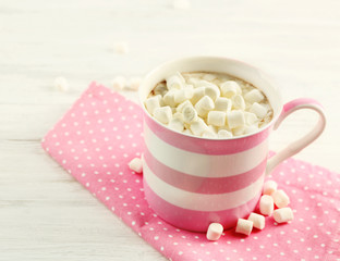 Mug of hot chocolate with marshmallows, on light wooden background