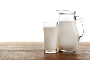 Milk in glass and in jar on table isolated on white background