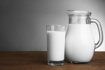 Milk in glass and in jar on table on light background