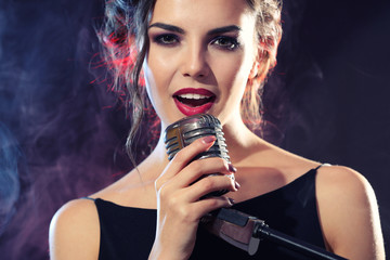 Young beautiful woman singing in colourful smoke, close up