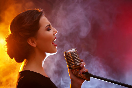 Elegant woman singing in colourful smoke, close up