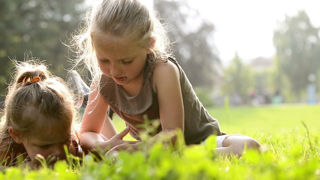 Sisters lay down are reading fairy tales at town park