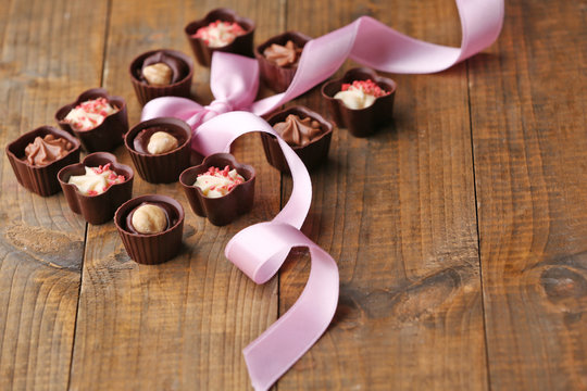 Set of chocolate candies with ribbon on a wooden background