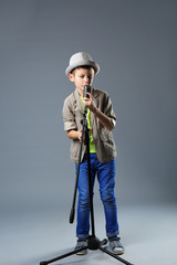 Little boy singing with microphone on a grey background