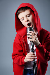 Little boy singing with microphone on a grey background