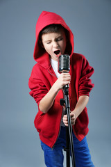 Little boy singing with microphone on a grey background